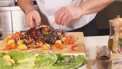 Adult Chef Decorates Roasted Turkey with Onions and Herbs