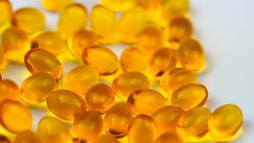 Falling Golden Capsules on White Background