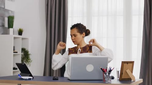 Woman Stretching at Desk in Bright Home Office