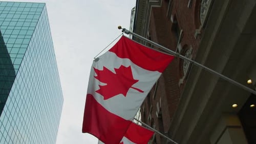 Canadian Flag Waves Next to Modern Building
