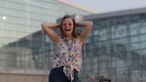Woman Dancing Happily Outside Modern Airport Building