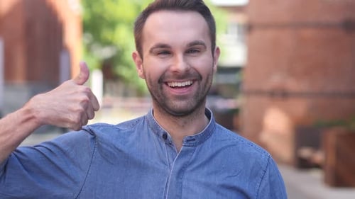 Thumbs Up By Casual Man at Work Looking at Camera