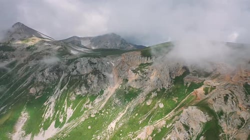 Epic Morning Mountain Landscape with Grass Covered Slope Under Moving Steam of Clouds. Aerial View