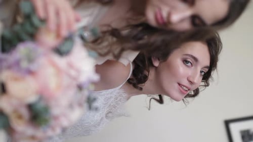 Two Women Posing with Flowers at Wedding