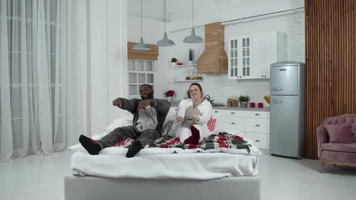 Couple in Pajamas Dancing on Bed Together
