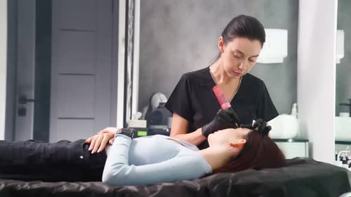 Woman Receiving Eyebrow Microblading Treatment in Beauty Salon