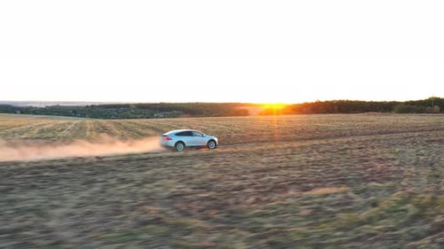 Car Driving Along Dirt Road at Sunset
