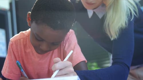 Teacher helping schoolboy with his homework in classroom