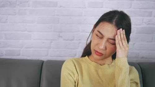 Woman with Headache Sitting on Couch