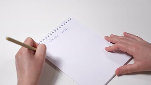 Closeup of Female Hands Writing with Left Hand the Goals for 2022