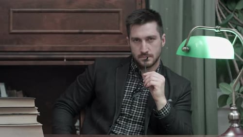 Beau jeune homme tenant des lunettes et regardant dans la caméra
