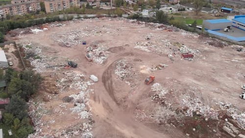 Construction waste dump, aerial view. Bulldozer pushes trash one heap
