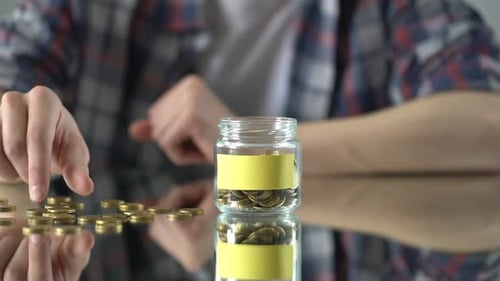 Man Puts Gold Coins into Savings Jar