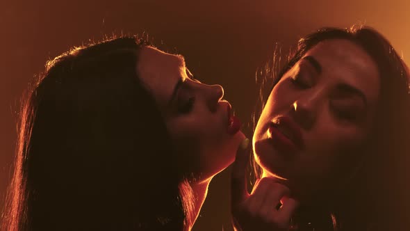 Two Lesbians Girls in Erotic Leather Lingerie Caress Each Other. Shot in a Dark Studio. Close Up Two Lesbians Girls in Erotic Leather Lingerie Caress Each Other. Shot in a Dark Studio. Close Up