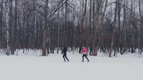 Man and Woman in the Winter Running Through the Park in Slow Motion