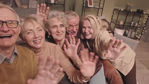 Group of Senior Friends Waving Indoors