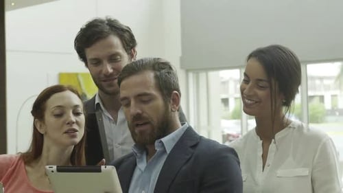 Coworkers Gather Around Tablet in Office Lobby