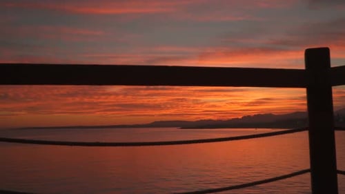 The Mountains and the Sea At Sunset. View Through Fence