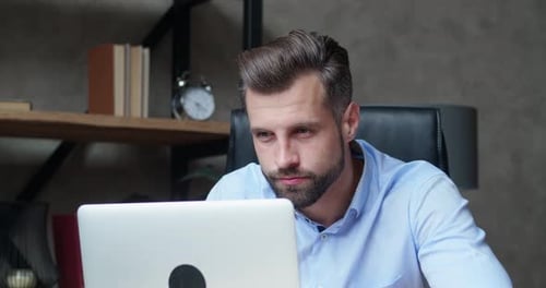 Stressed Adult Uses Laptop in Workplace