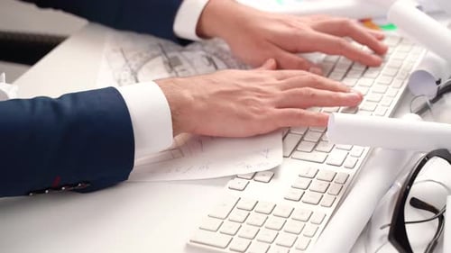 Ingenieur, der zwischen Projekten im Büro die Tastatur verwendet.