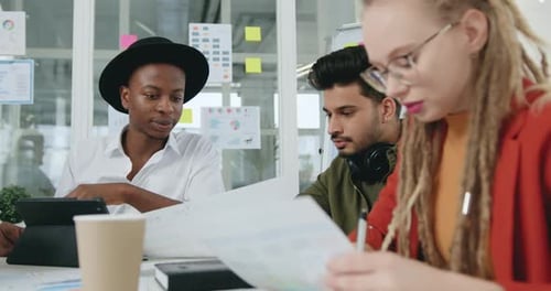 Collègues travaillant sur des articles et parcourant des rapports à l'aide de graphiques dans le cadre d'un projet conjoint