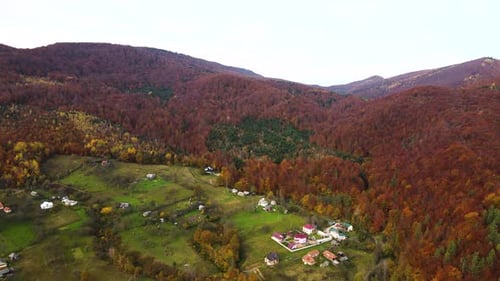 Aerial view of a village rural area with small houses between autumn mountain hills covered