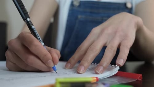 Person Writing in Notebook at Table Close Up
