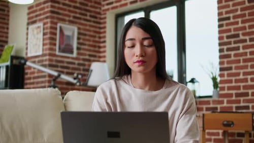 Woman Using Laptop in Brick-Walled Living Room