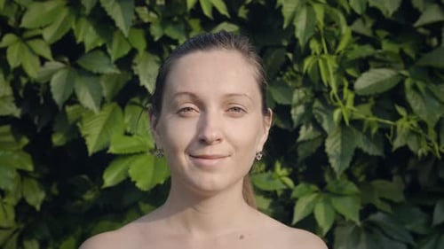 Woman Poses Outdoors in Front of Green Leaves
