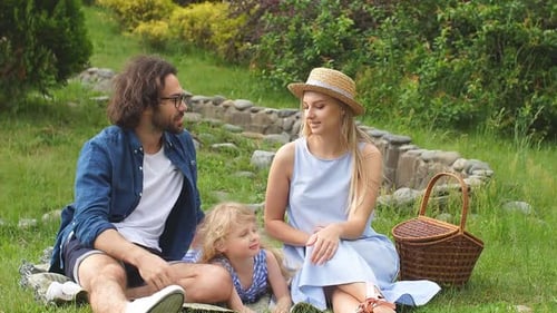 Happy Family on Picnic in Field on Sunny Summer Day Enjoying and Resting