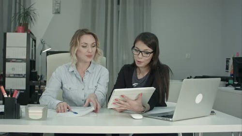 Lächelndes weibliches Business-Team arbeitet mit Tablet-PC im Büro