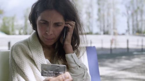 Woman Talks on Phone While Holding Credit Card