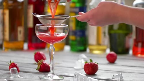 Strawberry Cocktail Being Poured into Glass with Strainer