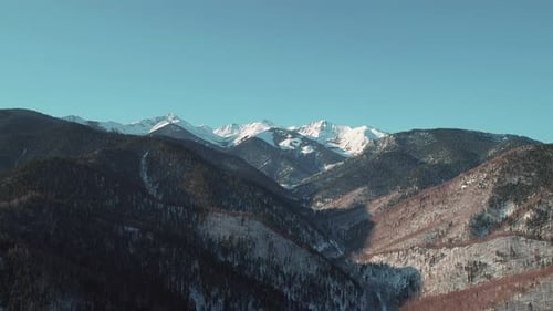 Aerial Landscape Mountains Covered with Forest and Snowcapped Peaks in the Background