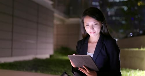 Woman Using Tablet at Night in Urban Setting