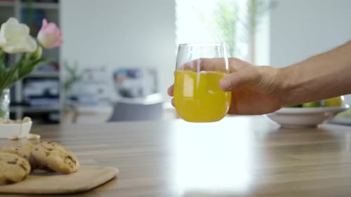 Hand Takes and Replaces Glass of Orange Juice