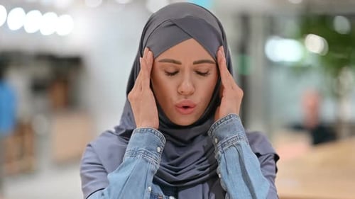 Woman in Hijab Experiencing Headache at Work