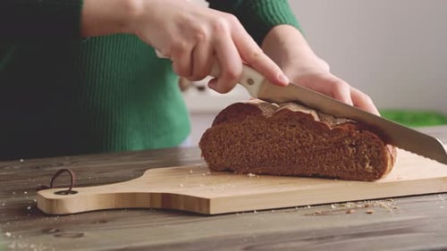 Cutting Brown Bread Loaf on Wooden Board