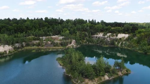 Luftaufnahme des Sees mit einer kleinen Insel und wunderschönem Wasser in einem Steinbruch, umgeben von Wald