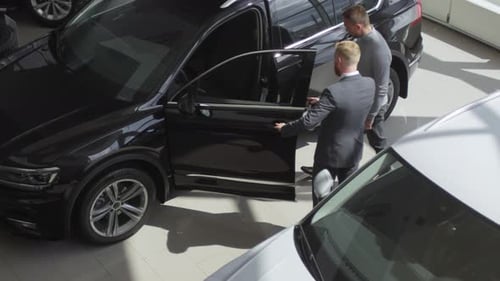 High Angle of Man Sitting in Car with Assistant of Seller in Auto Showroom