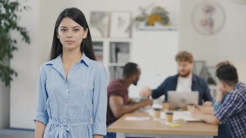 Portrait of Young Brunette Business Woman Looking at Camera and Smiling in Office Workplace
