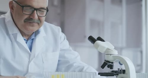 Male Research Scientist. He Sitting in a High-End Modern Laboratory with Beakers, Glassware