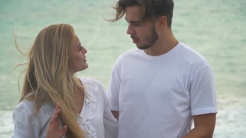Young Couple Talking in Slow Motion in the Background of the Sea. Man and Woman in White Dress Have
