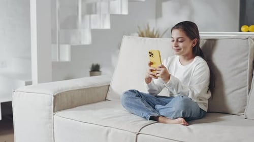 Girl Uses Smartphone While Sitting on Couch