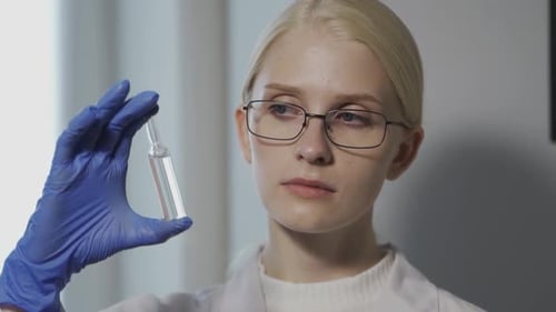 Young Scientist Examining Vial and Rat in Lab