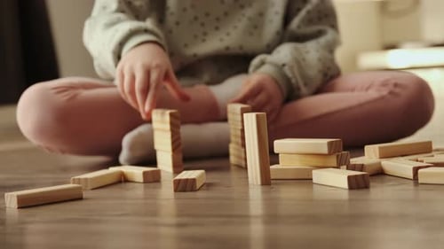 Un niño pequeño juega un juego de mesa, el niño construye con bloques de ladrillos de madera.