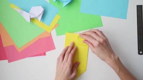 Hands Fold Paper into Origami at Table