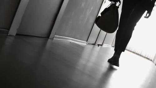 Woman Walking Along Hallway with Bag