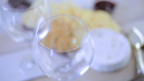 Pouring White Wine Near Cheese and Chips