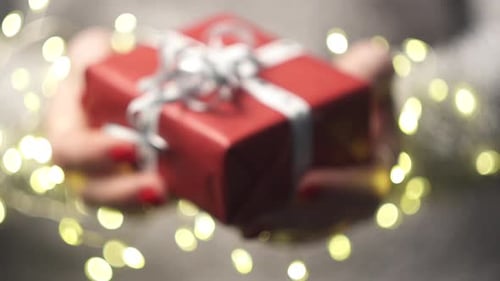 Female Hands Hold Forward a Box with a Gift, Close-up.